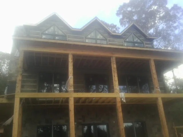 Dormers and porch framing on a large log home under construction — Roof Coating work by our crew in Locust Dale