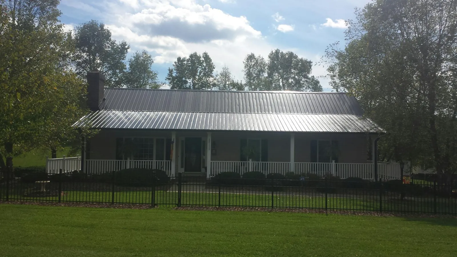 Gray metal roof on a brick ranch with a full width front porch — Gutter Guard Installation work by our crew in Locust Dale