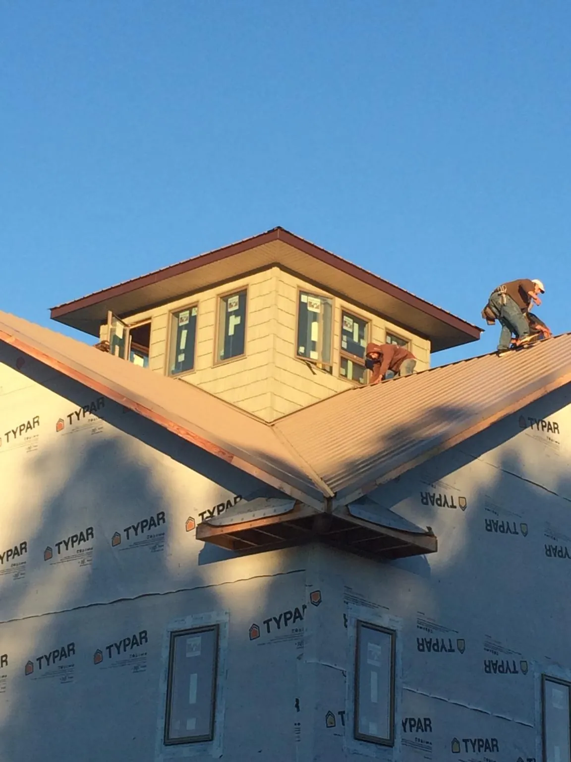 Roofers working around a rooftop cupola on a new metal roof at sunset — Roof Waterproofing in Locust Dale by Roofing Brothers